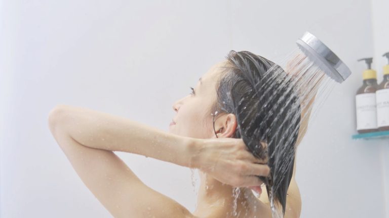 シャワーで髪を洗い流す女性